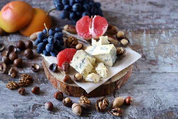 Foto cheeseboard käse mit nüssen grapefruit und trauben auf einem holzbrett gesunde snacks