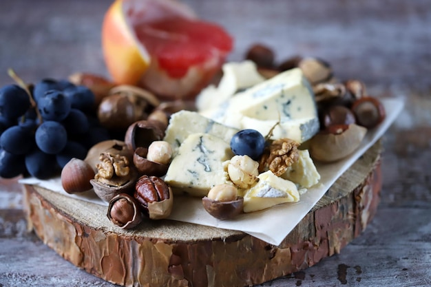 Cheeseboard Käse mit Nüssen Grapefruit und Trauben auf einem Holzbrett Gesunde Snacks