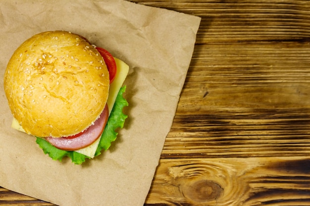 Cheeseburger caseiro delicioso fresco em papel pardo na mesa de madeira Vista superior