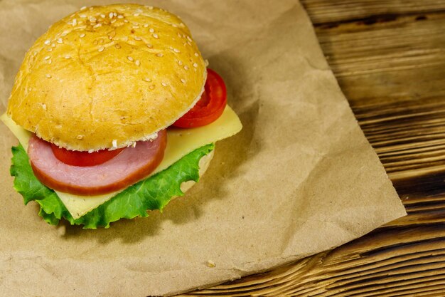 Cheeseburger caseiro delicioso fresco em papel pardo na mesa de madeira