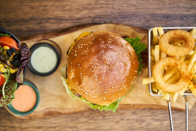 Cheeseburger com batatas fritas na mesa de madeira