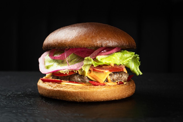 Foto cheeseburger com costeleta de carne e cheder de queijo em um fundo preto