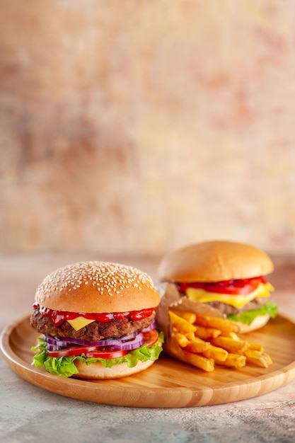 Cheeseburger de carne deliciosa com batata frita na superfície da luz da tábua de corte