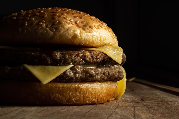 cheeseburger de carne dupla sobre superfície de madeira e fundo preto