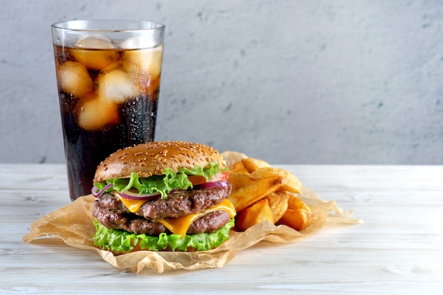 Cheeseburger duplo com batatas fritas e um copo de coca-cola