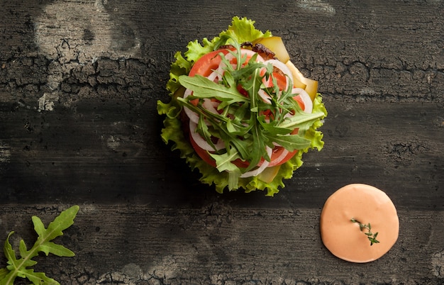 Cheeseburger em uma velha superfície de madeira de hambúrguer de cor escura com molho e ketchup