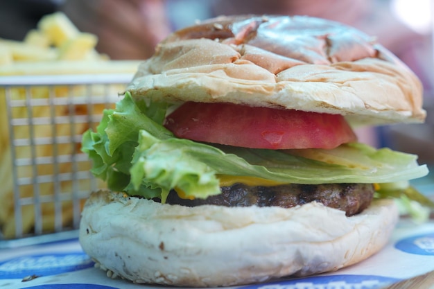 Foto cheeseburger con ensalada y tomate en una tabla de madera