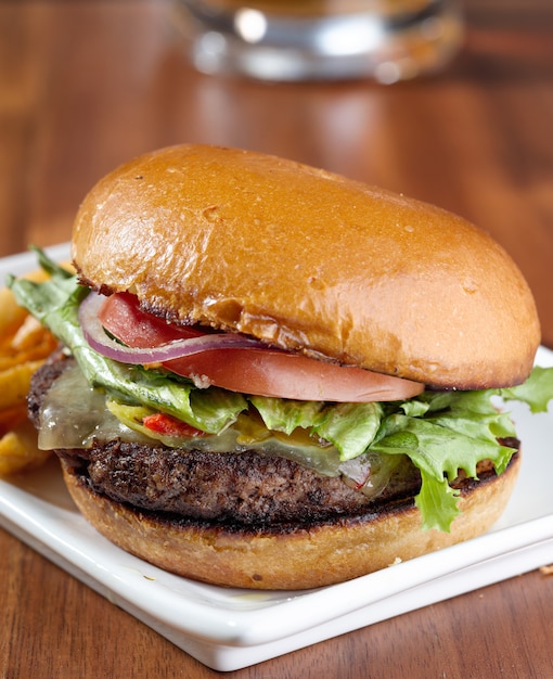 Cheeseburger gourmet com uma caneca de cerveja no fundo