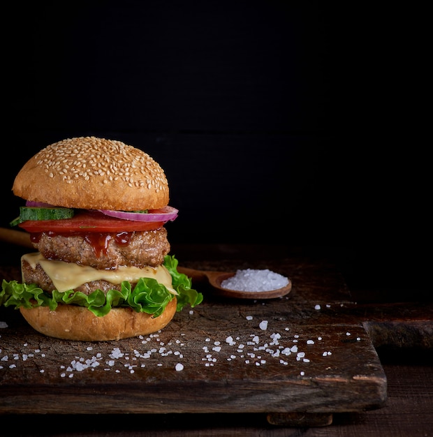 Cheeseburger in einem Brötchen mit Samen des indischen Sesams, im mittleren Frischgemüse