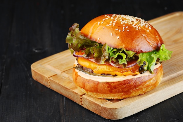 Cheeseburger mit Rindfleisch, Gemüse und Salat auf Holz. Burger Nahaufnahme