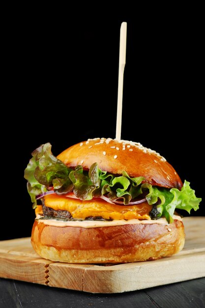 Cheeseburger mit Rindfleisch, Gemüse und Salat auf Holz. Burger Nahaufnahme