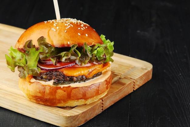 Cheeseburger mit Rindfleisch, Gemüse und Salat auf Holz. Burger Nahaufnahme