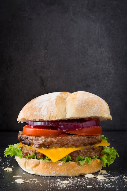 Cheeseburgers e vegetais deliciosos no preto