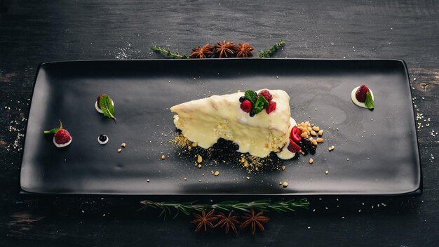 Cheesecake com frutas e frutas secas Sobremesa Em um fundo preto de madeira Copie o espaço