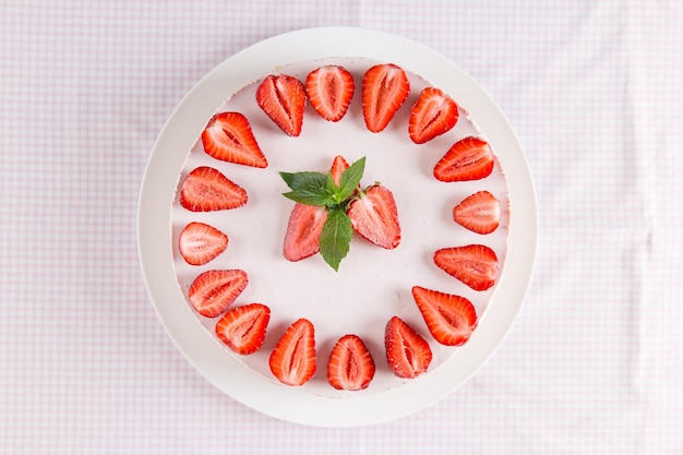 Cheesecake com morangos e hortelã sobre uma mesa com uma toalha de mesa leve café da manhã caseiro doce copiar espaço