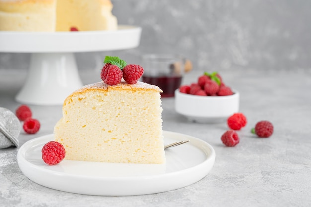 Cheesecake de algodão japonês em um suporte sobre fundo cinza de concreto com framboesas frescas