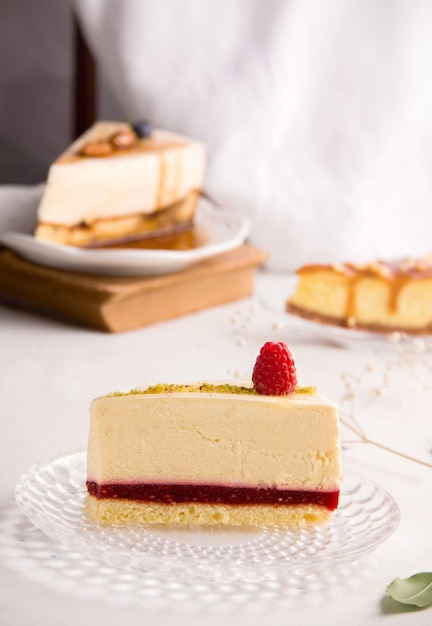 Foto cheesecake de baunilha com geleia de framboesa em um fundo claro com pedaços de outras sobremesas