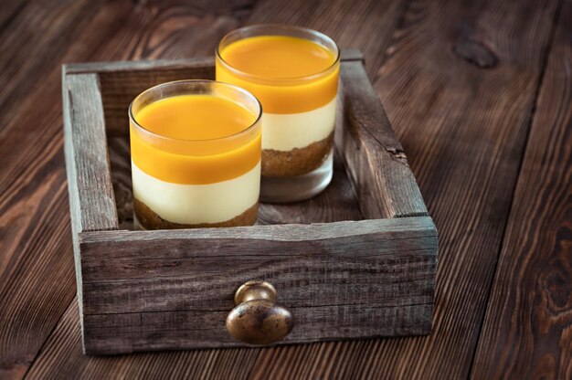 Cheesecake de manga servido nos copos em superfície rústica