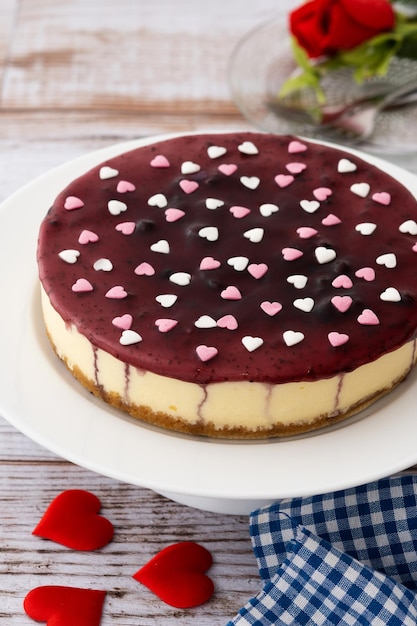 Cheesecake de mirtilo decorado com corações doces na mesa de madeira