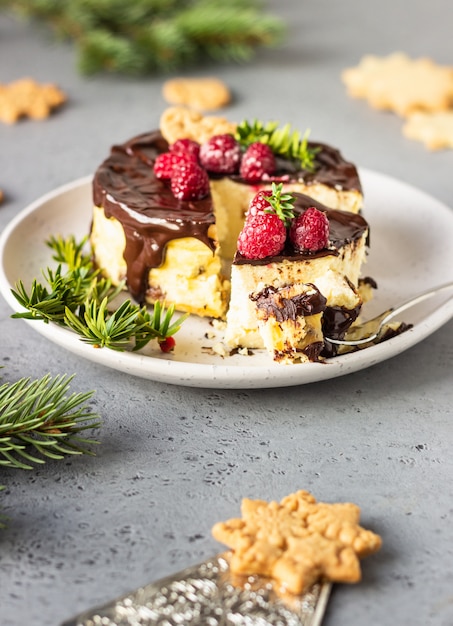 Cheesecake de Nova York com ganache de chocolate, framboesas e biscoitos com ramos de abeto.