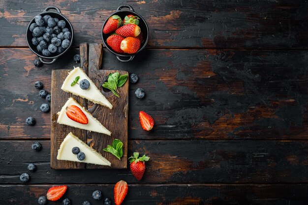 Cheesecake de Nova York ou cheesecake clássico com frutas frescas, no fundo da velha mesa de madeira escura, vista de cima plana, com espaço de cópia para o texto