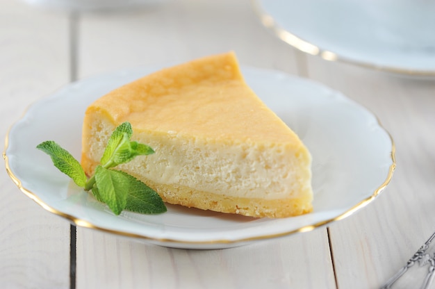 Cheesecake e uma folha de hortelã no pires com uma borda dourada