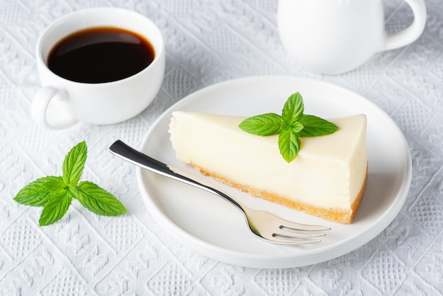 Cheesecake e xícara de café preto em uma mesa branca