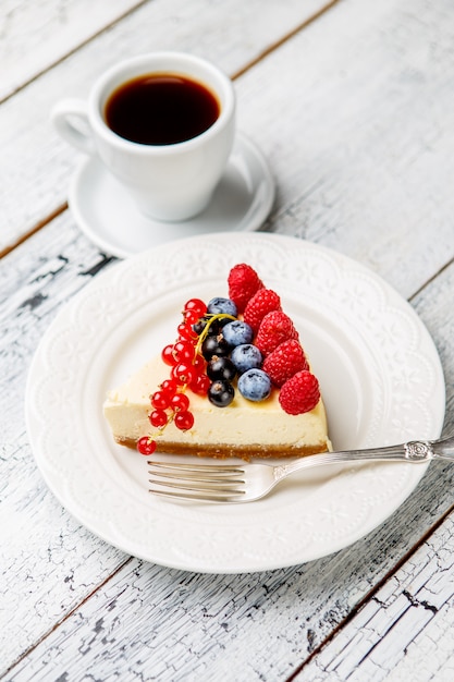 Cheesecake de frambuesa y arándano en mesa de madera