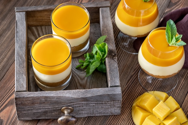 Cheesecake de mango servido en vasos sobre superficie rústica