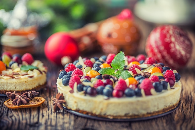 Foto cheesecake navideño con frutas frescas, bayas, fresas, frambuesas y anís estrellado.