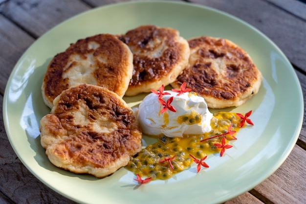 Cheesecakes com maracujá e creme de leite em um prato verde no café da manhã.