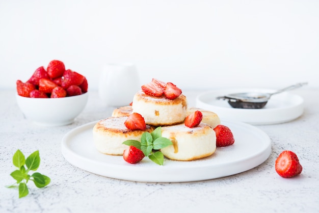 Cheesecakes de queijo cottage com morangos e açúcar de confeiteiro