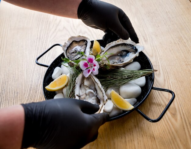 Foto chef abre una ostra fresca. plato con ostras abiertas. restaurante.