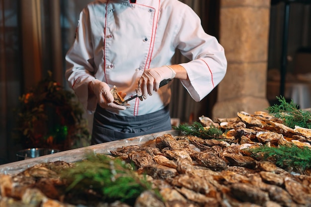 Foto el chef abre ostras en el restaurante.