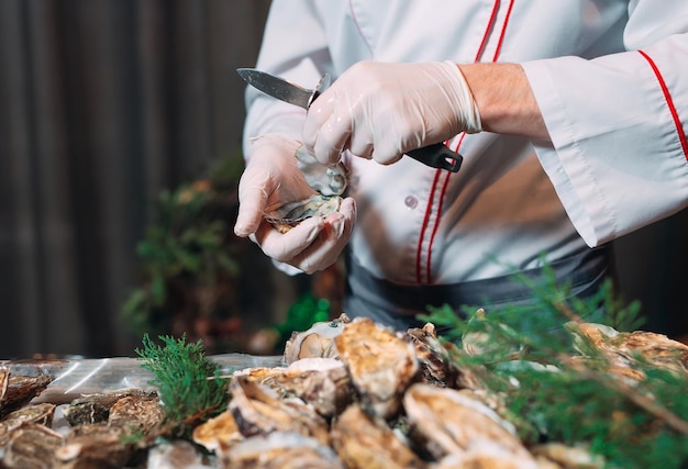 El chef abre ostras en el restaurante.