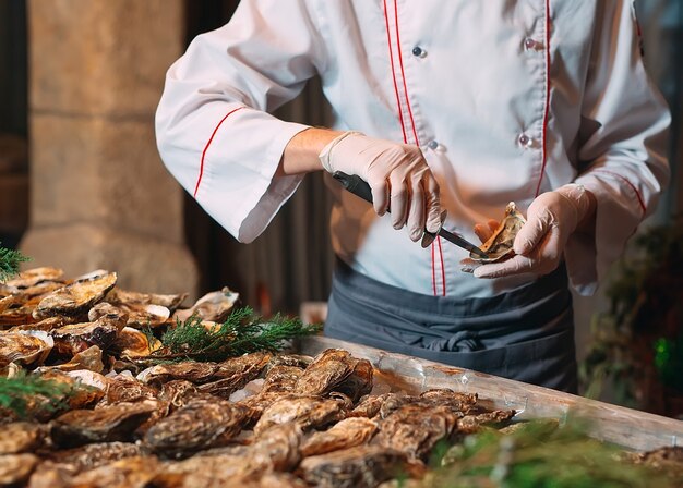 El chef abre ostras en el restaurante.