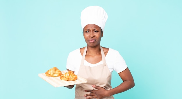 Chef adulto afroamericano negro mujer sosteniendo una bandeja de croissants