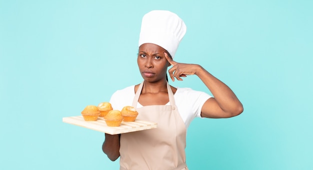 Chef adulto afroamericano negro mujer sosteniendo una bandeja de muffins