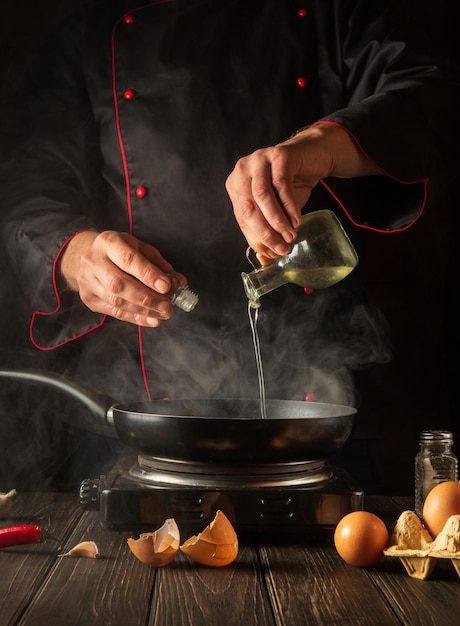 El chef agrega aceite dulce mientras cocina huevos en una sartén.