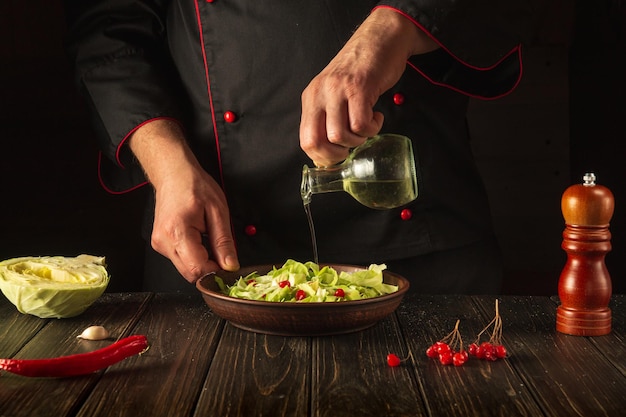 El chef agrega aceite a una ensalada de verduras frescas