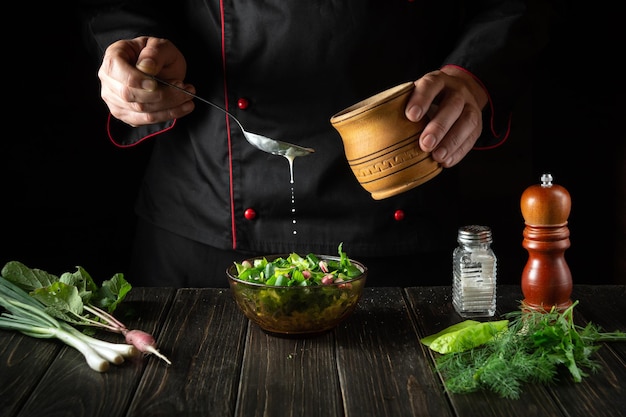 El chef agrega crema agria a una ensalada de verduras frescas Cocina deliciosa comida en la cocina