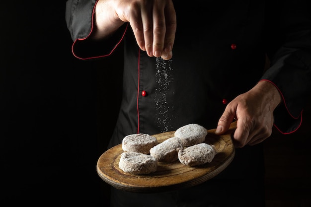 El chef agrega sal a las chuletas en una tabla para cortar Cocinar empanadas de carne para una hamburguesa