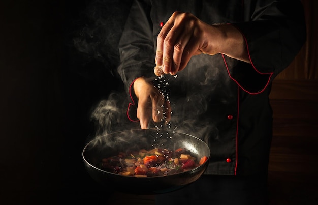 Foto el chef agrega sal a una sartén caliente humeante