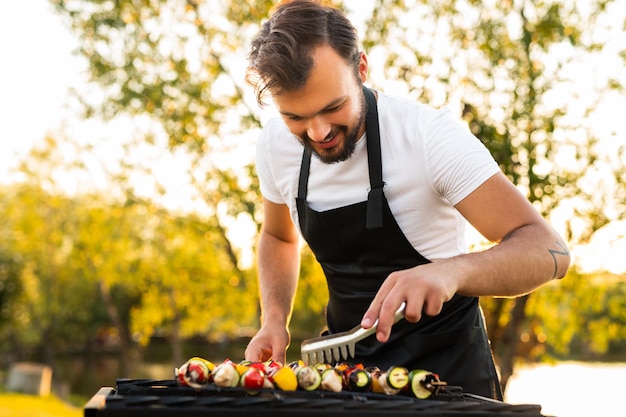 Chef alegre grelhar espetos na zona rural