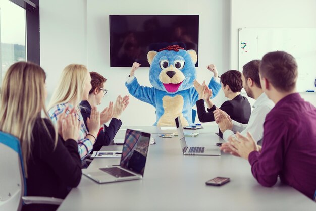 Chef als Teddybär verkleidet, der Spaß mit Geschäftsleuten in modernen Firmenbüros hat