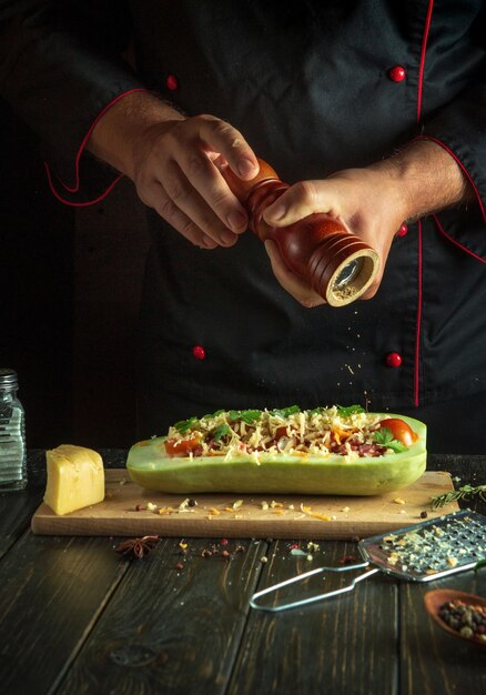 El chef añade pimienta a los calabazos en la mesa de la cocina