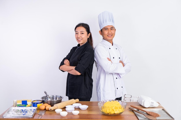 Chef asiático masculino e feminino em pé com as mãos cruzadas