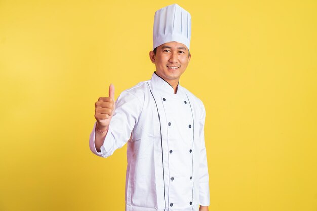 Foto chef asiático sonriente con los pulgares en alto en un fondo aislado