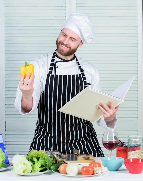 Foto chef barbudo cozinhando comida guy leu receitas de livros conceito de artes culinárias homem aprende receita melhora a habilidade culinária guia de culinária final para iniciantes livro receitas familiares de acordo com a receita