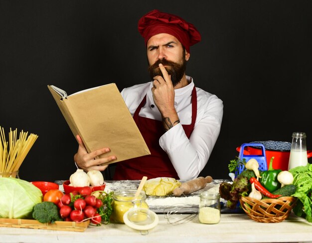 El chef barbudo prepara comidas en la mesa de la cocina